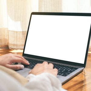 main d'homme tapant sur le clavier d'un ordinateur portable à l'écran blanc